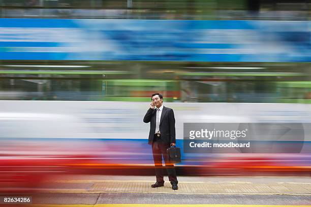 china, hong kong, business man using mobile phone, standing on street, long exposure - overlap stock-fotos und bilder