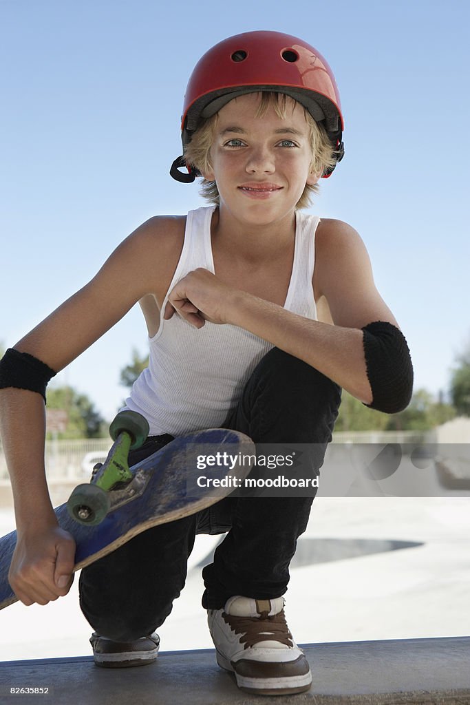 Teenage boy (13-15) with skateboard at skateboard park, portrait