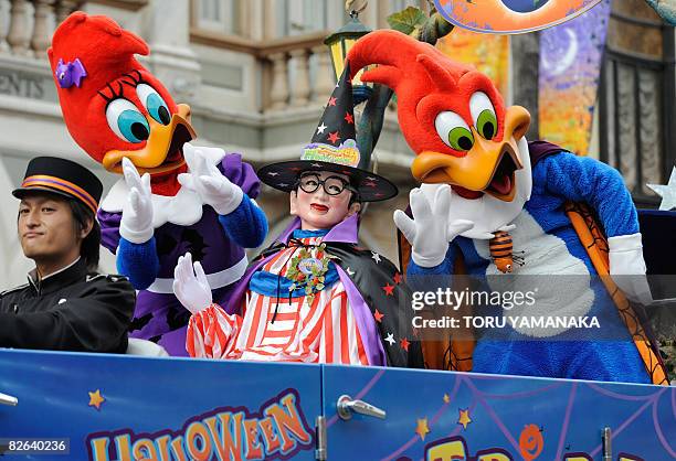 People clad in Halloween costumes, Woody Woodpecker , Winnie Woodpecker and local famous character "Kuidaore Taro" wave to the audience from a...