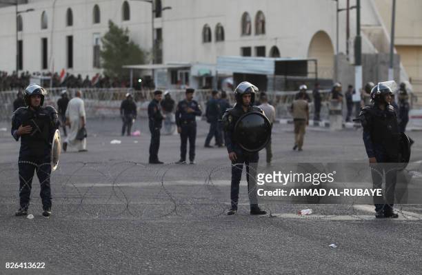 Iraqi forces stand guard outside the Green zone as supporters of cleric Moqtada al-Sadr attend a demonstration in Tahrir Square, central Baghdad, on...