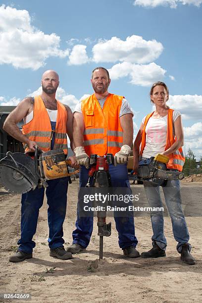 3 construction workers holding machinery - construction-worker stockfoto's en -beelden