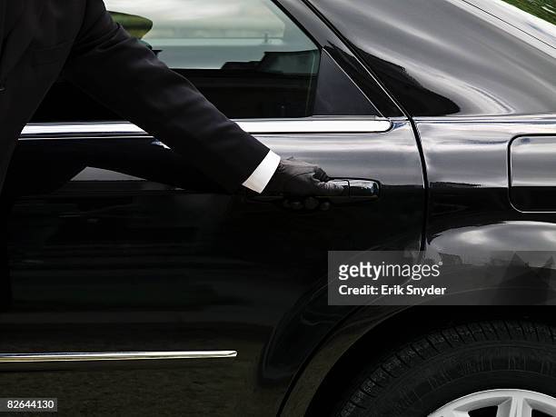 chauffeur opening limousine door. - limousine photos et images de collection
