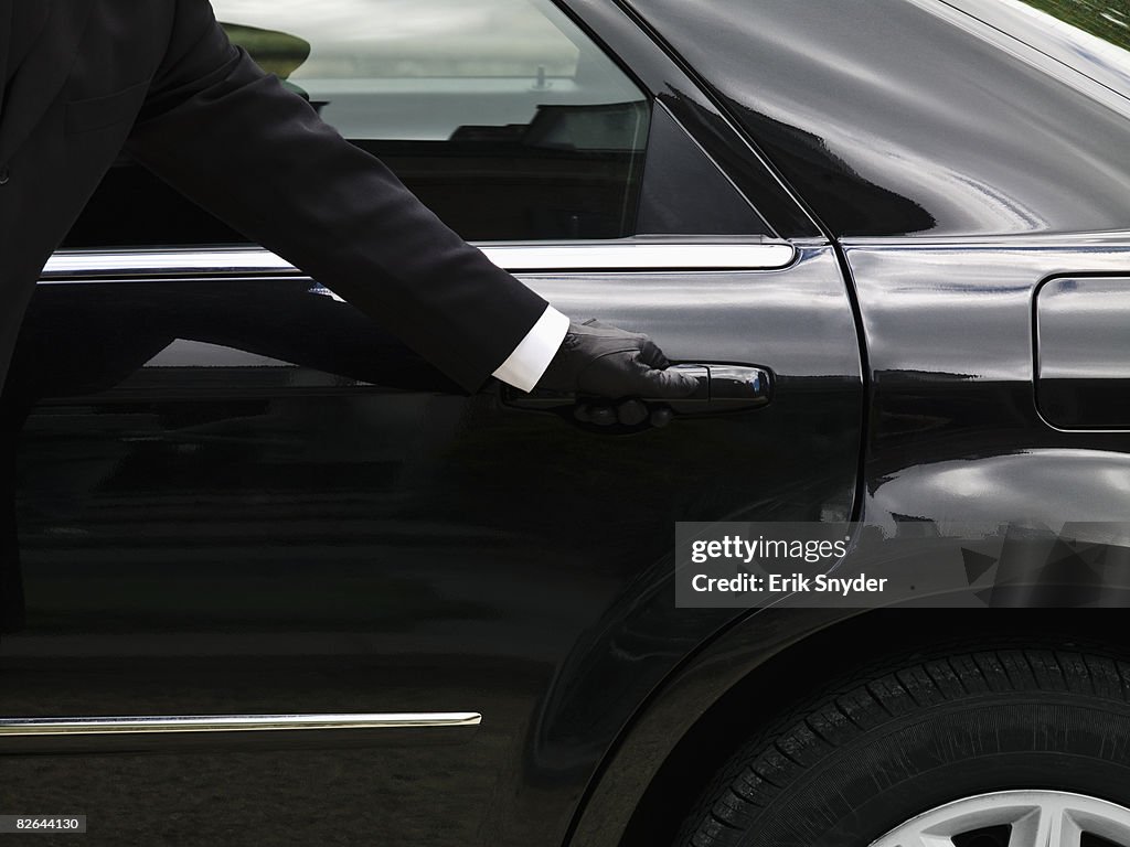 Chauffeur opening limousine door.