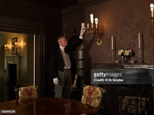butler changing evergy saver lightbulb. - huishoudelijke dienstverlening stockfoto's en -beelden