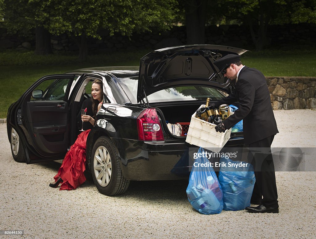 Chauffeur putting recycling in car boot