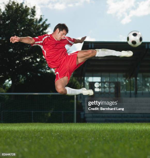 soccer player leaping to kicking football - moosinning stock pictures, royalty-free photos & images