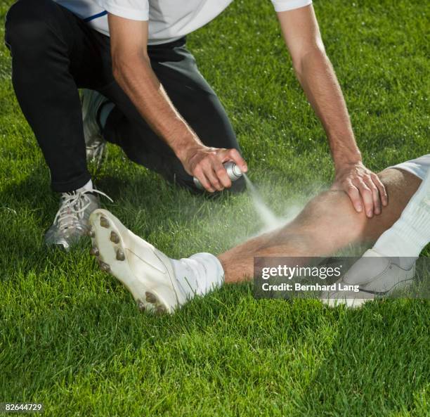 man spraying leg of soccer player - injured football player stock pictures, royalty-free photos & images