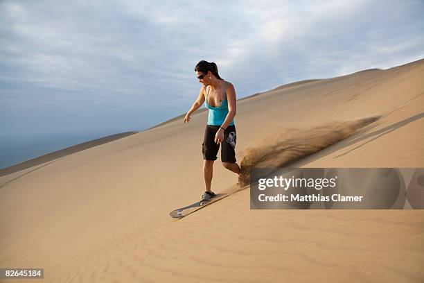 young woman sandboards down a dune - sand boarding stock pictures, royalty-free photos & images