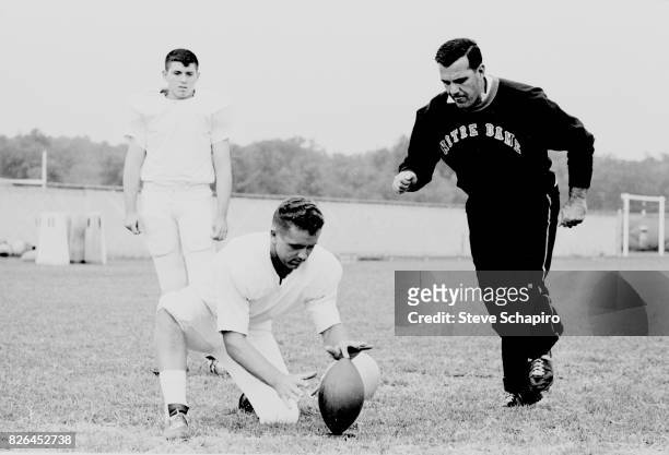 American college football coach Ara Parseghian , of the University of Notre Dame, demonstrates place kicking on the field during a team practice,...