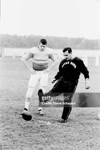 American college football coach Ara Parseghian , of the University of Notre Dame, demonstrates place kicking on the field during a team practice,...