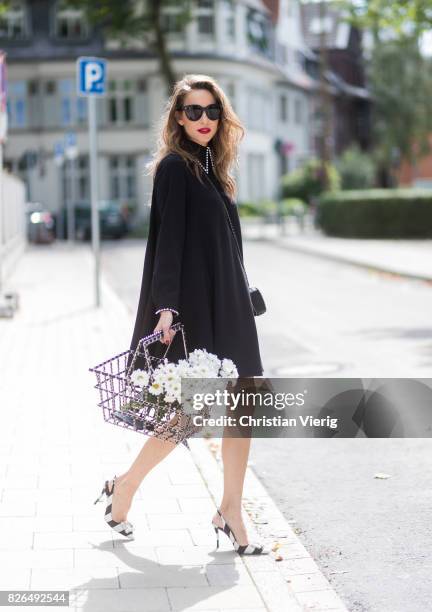 Model and fashion blogger Alexandra Lapp wearing a black shirt dress from Steffen Schraut, Celine Audrey sunglasses, flower satin sling-back pumps...