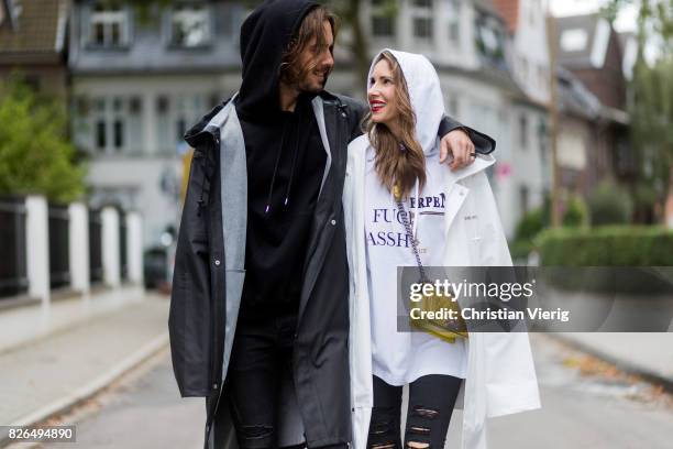 Couple look a like holding arms in front of a DHL van - Model and Blogger Alexandra Lapp wearing oversized raincoat with a hood in white from...