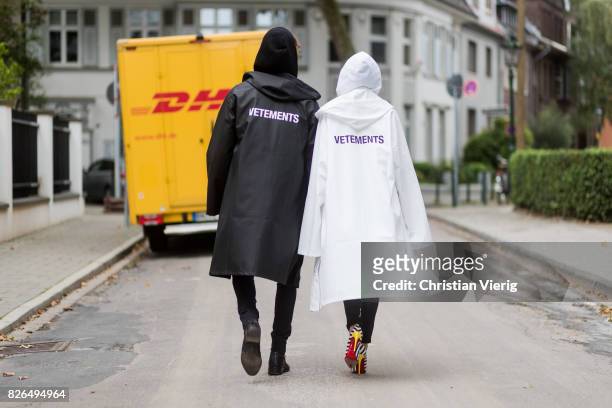 Couple look a like holding arms in front of a DHL van - Model and Blogger Alexandra Lapp wearing oversized raincoat with a hood in white from...