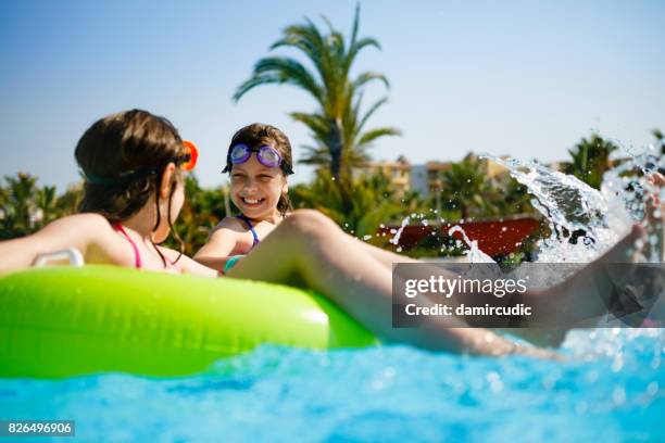 kids having fun on innertubes in swimming pool - lido stock pictures, royalty-free photos & images