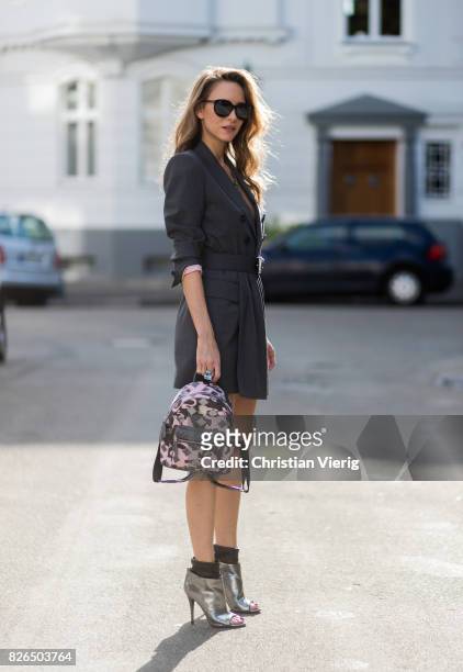 Model and fashion blogger Alexandra Lapp wearing a blazer dress in grey by Dsquared with matching waist belt, Chanel broach, camouflage Stark...