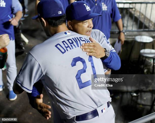 Yu Darvish of the Los Angeles Dodgers is congratulated by manager Dave Roberts after Darvish came into the dugout after the seventh inning against...