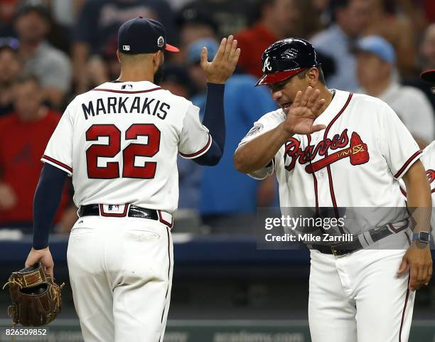 Right fielder Nick Markakis of the Atlanta Braves is congratulated by first base coach Eddie Perez after the game against the Miami Marlins at...