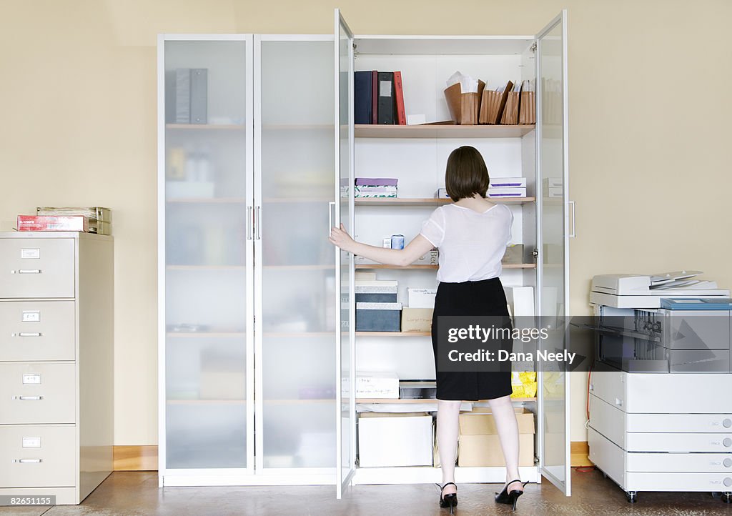 Young businesswoman looking inside cabinet