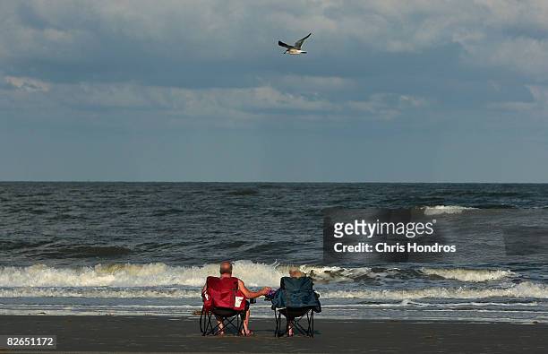 Couple watches the waves crash against the beach from chairs September 3, 2008 in Tybee Island, Georgia. Hurricane Hanna poses a potential threat to...