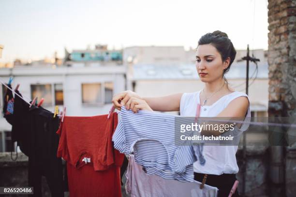 young woman hanging laundry on the rooftop - hanging stock pictures, royalty-free photos & images