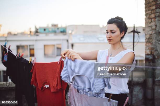 jovem mulher pendurando roupa no telhado - draped - fotografias e filmes do acervo