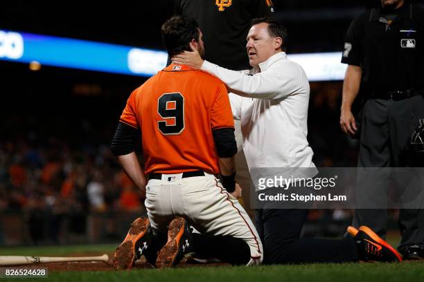 Brandon Belt of the San Francisco Giants is being tended to by head athletic trainer Dave Groeschner after being hit by a pitch during the sixth...