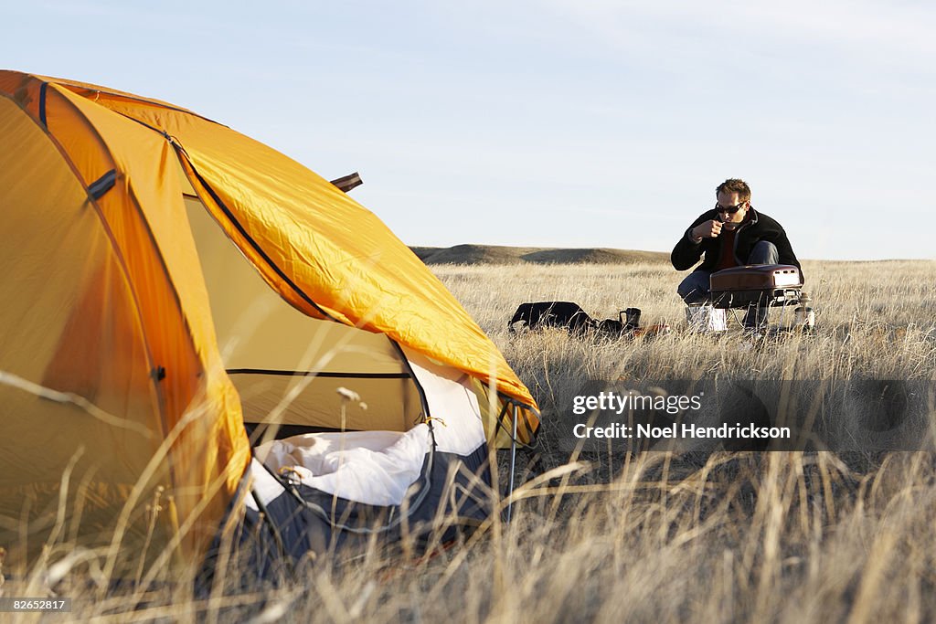 Man cooking near tent in field