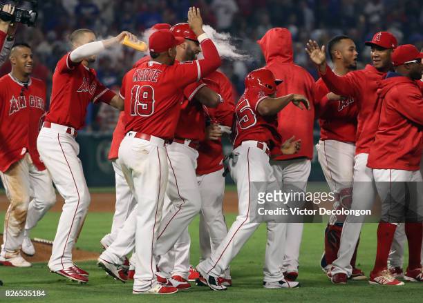 Andrelton Simmons of the Los Angeles Angels of Anaheim douses teammate Ben Revere after Revere scored on a passed ball which led to the game-winning...