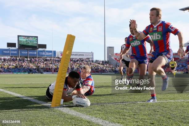 David Fusitu'a of the Warriors scores a try with Trent Hodkinson of the Knights in defence during the round 22 NRL match between the Newcastle...