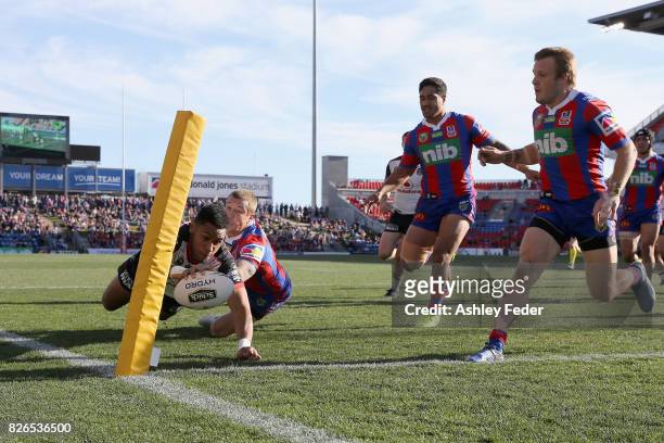 David Fusitu'a of the Warriors scores a try with Trent Hodkinson of the Knights in defence during the round 22 NRL match between the Newcastle...