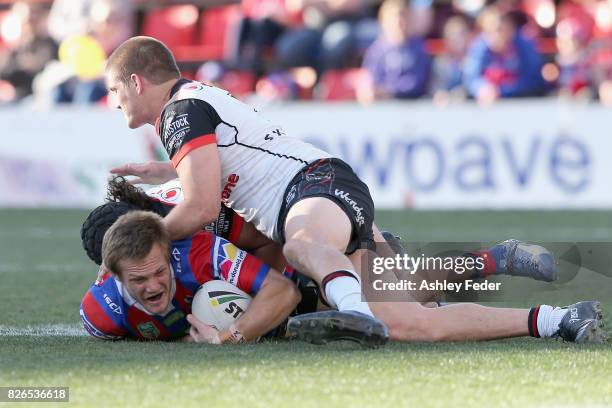 Nathan Ross is tackled by the Warriors defence during the round 22 NRL match between the Newcastle Knights and the New Zealand Warriors at McDonald...