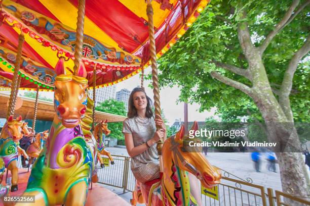 fröhliche frau, die spaß am karussell - carousel horses stock-fotos und bilder