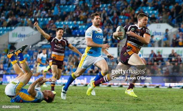 Corey Oates of the Broncos breaks the tackle of Kane Elgey to score a try during the round 22 NRL match between the Gold Coast Titans and the...
