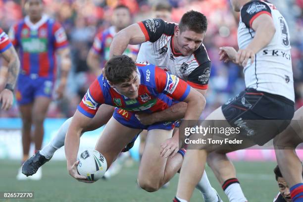 Sam Stone of the Knights is tackled by the Warriors defence during the round 22 NRL match between the Newcastle Knights and the New Zealand Warriors...