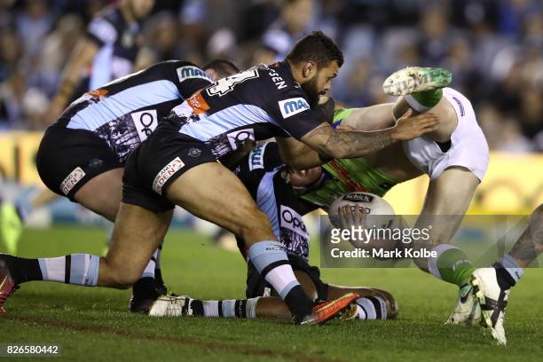 Luke Bateman of the Raiders is tackled by Jayson Bukuya of the Sharks during the round 22 NRL match between the Cronulla Sharks and the Canberra...