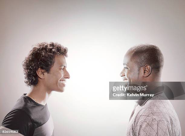 two men facing each other and smiling - faccia a faccia foto e immagini stock
