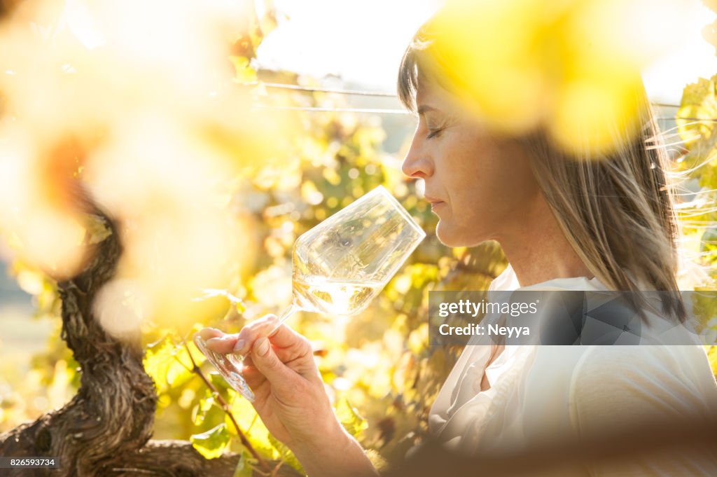 Weibliche Winzer mit Glas Weißwein auf Weingut