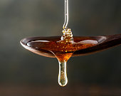 Honey pouring on wooden spoon and dripping from spoon