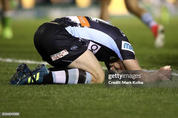 Luke Lewis of the Sharks grimaces as he catches his breath on the ground during the round 22 NRL match between the Cronulla Sharks and the Canberra...