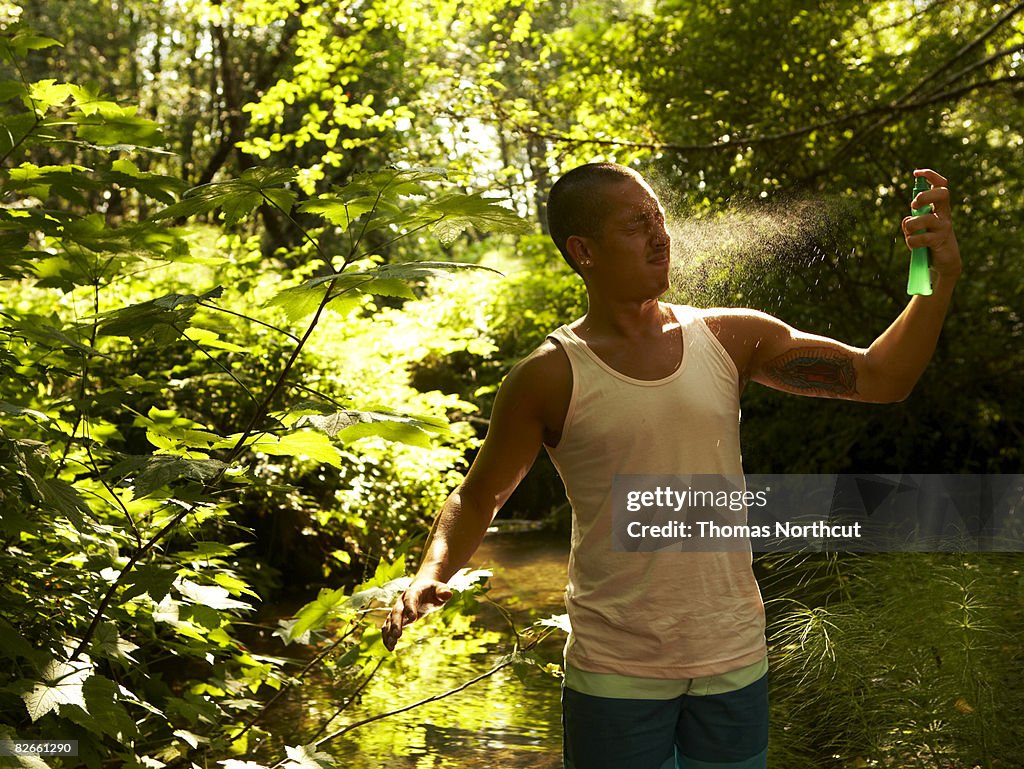 Young man spraying bug spray