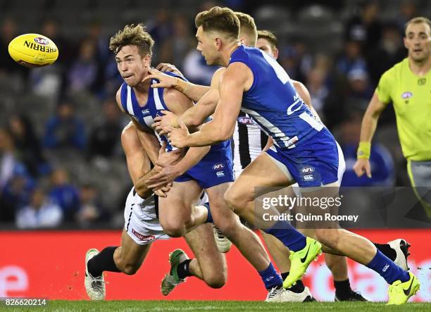 Trent Dumont of the Kangaroos handballs whilst being tackled during the round 20 AFL match between the North Melbourne Kangaroos and the Collingwood...