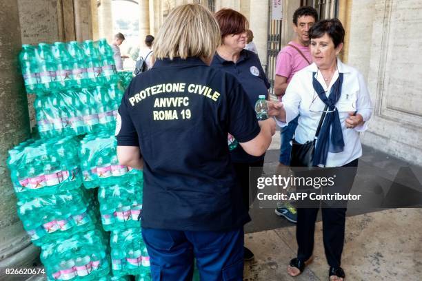 Members of the Italian Civil Protection distribute water bottles to citizens and tourists at the Campidoglio in central Rome on August 5, 2017 as...