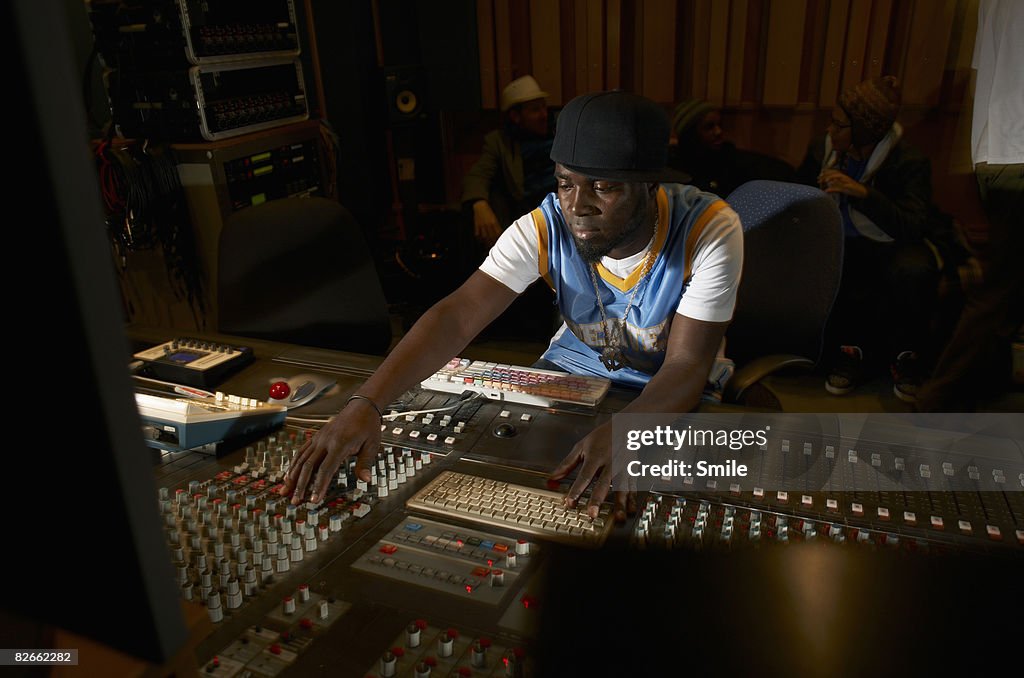 Man working at mixing desk group chatting in back