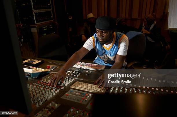 man working at mixing desk group chatting in back - trabalho de entretenimento - fotografias e filmes do acervo