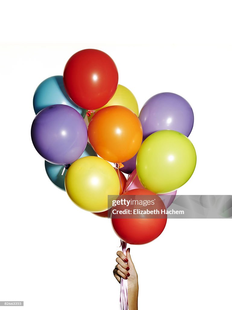 Hand holding a bunch of multi-coloured balloons