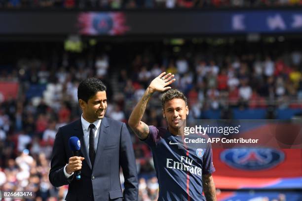 Paris Saint-Germain's Brazilian forward Neymar , flanked by Paris Saint Germain's Qatari president Nasser Al-Khelaifi , waves to the crowd during his...