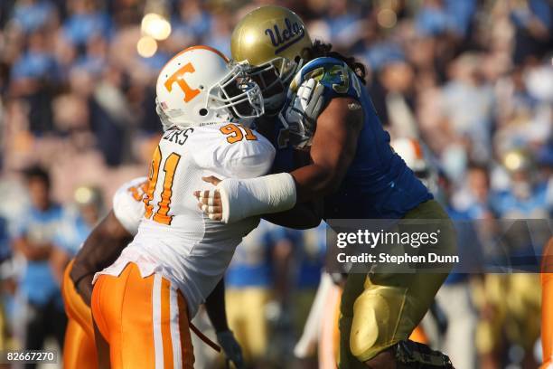 Tackle Micah Kia of the UCLA Bruins and defensive end Robert Ayers of the University of Tennessee Volunteers battle on the line of scrimmage on...