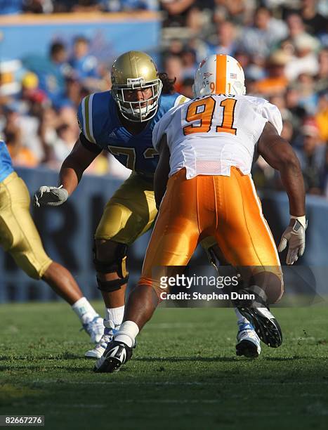 Tackle Micah Kia of the UCLA Bruins and defensive end Robert Ayers of the University of Tennessee Volunteers battle on the line of scrimmage on...