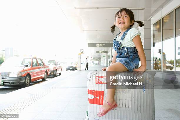 a girl rides suitcase by cabstand in airport - michael sit stock pictures, royalty-free photos & images