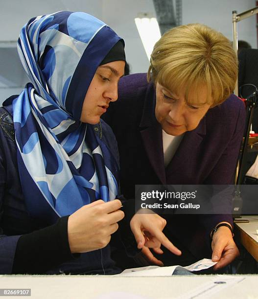 German Chancellor Angela Merkel speaks with a young Muslim woman training to become a seamstress at the BildungsWerk Kreuzberg, a vocational training...